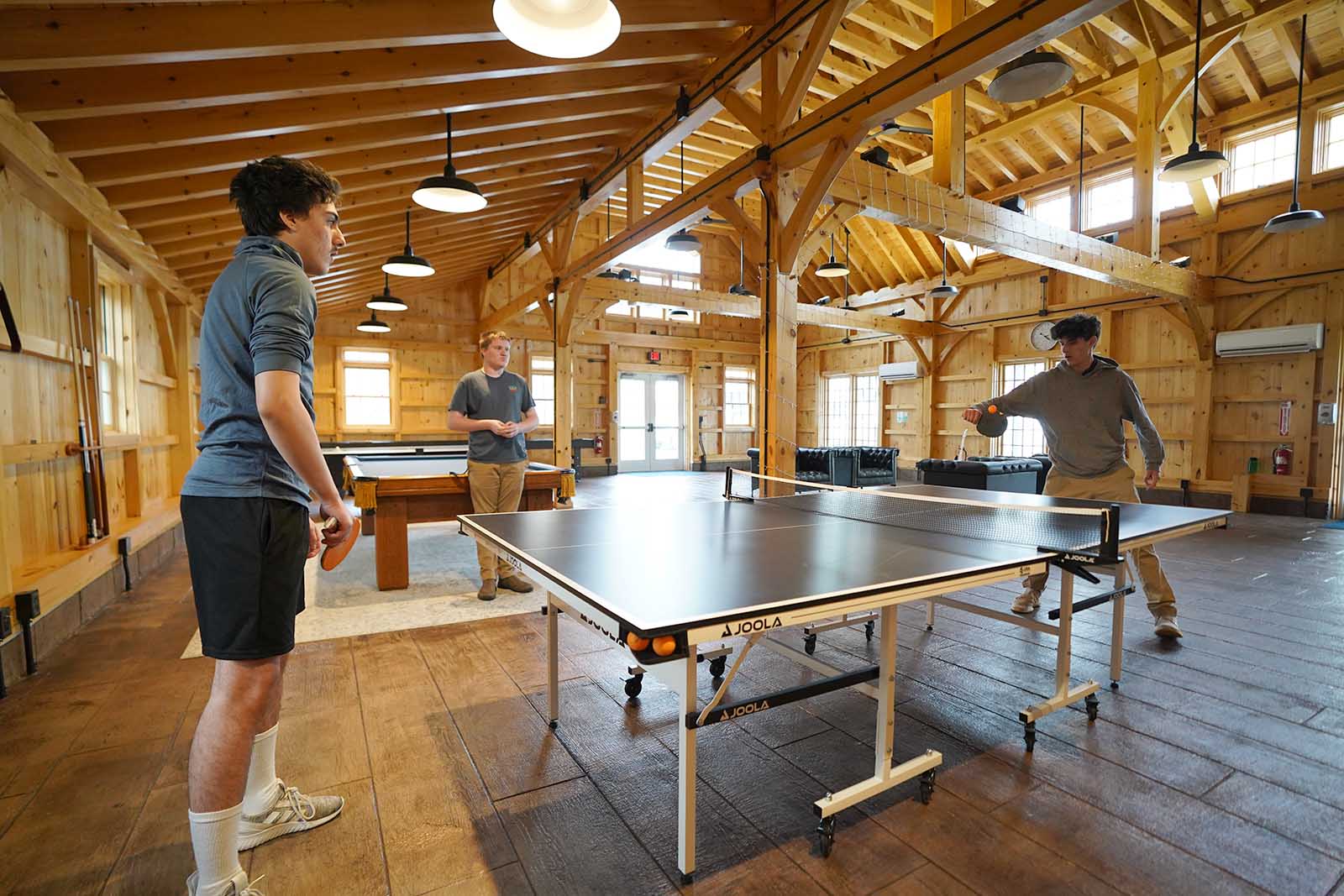Two men playing ping pong in a log cabin.